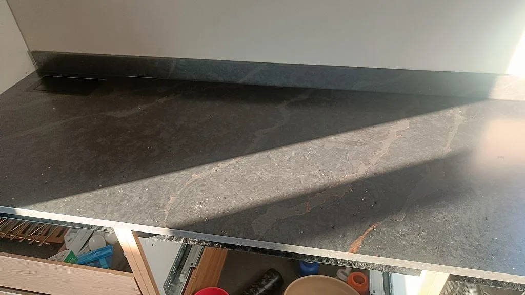 Mörk matt Silestone Bohemian Flame som lång köksbänkskiva över trästommar med 12 mm stänkskydd i Kävlinge.