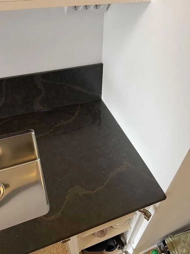 Närbild på polerad Silestone Bohemian Flame som kompositbänkskiva med rostfri diskho och mörk ådring i Limhamn.