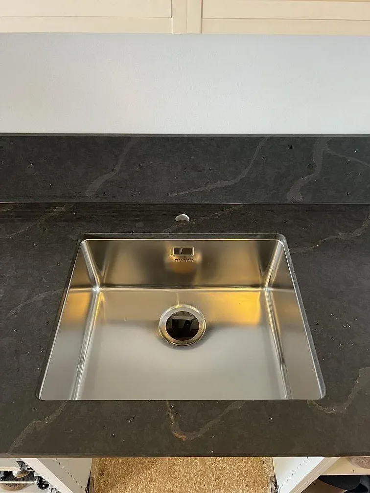 Underlimmad rostfri diskho i polerad Silestone Bohemian Flame med 12 mm stänkskydd i ett kök i Limhamn.