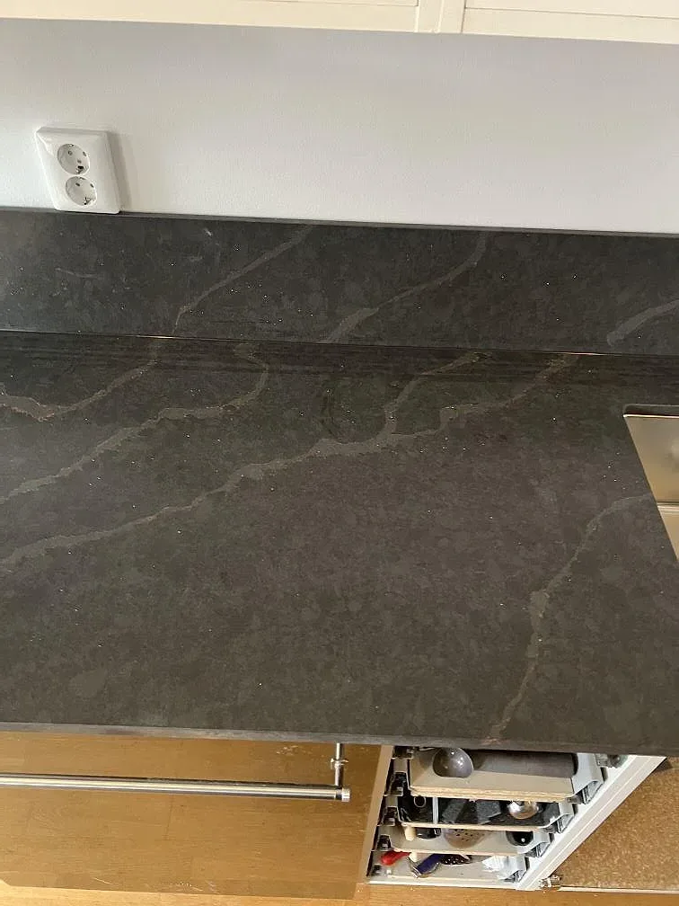 Polerad Silestone Bohemian Flame som köksbänkskiva och stänkskydd med mörk ådring i ett Limhamn-kök.