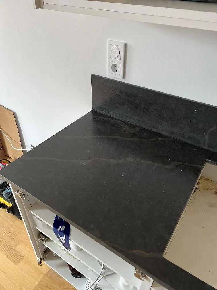 Polerad kompositbänkskiva i Silestone Bohemian Flame vid hällöppning och uppvikt stänkskydd i Limhamn.