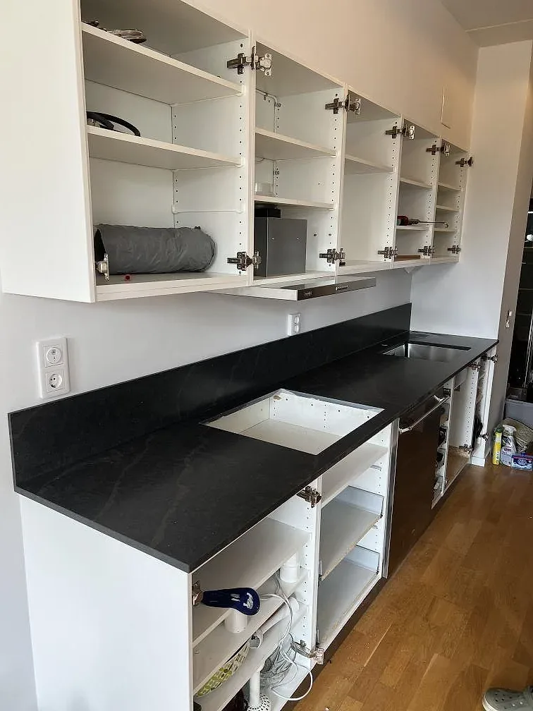 Köksbänkskiva i mörk Silestone Bohemian Flame, polerad komposit, med stänkskydd, diskho och hällöppning i ett kök i Limhamn.