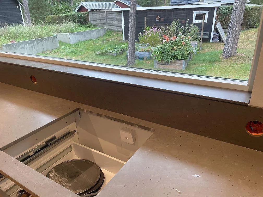 Bänkskiva i Silestone Brass Relish, matt Mocka komposit, med hällurtag och låg stänkkant under köksfönster i Åhus.