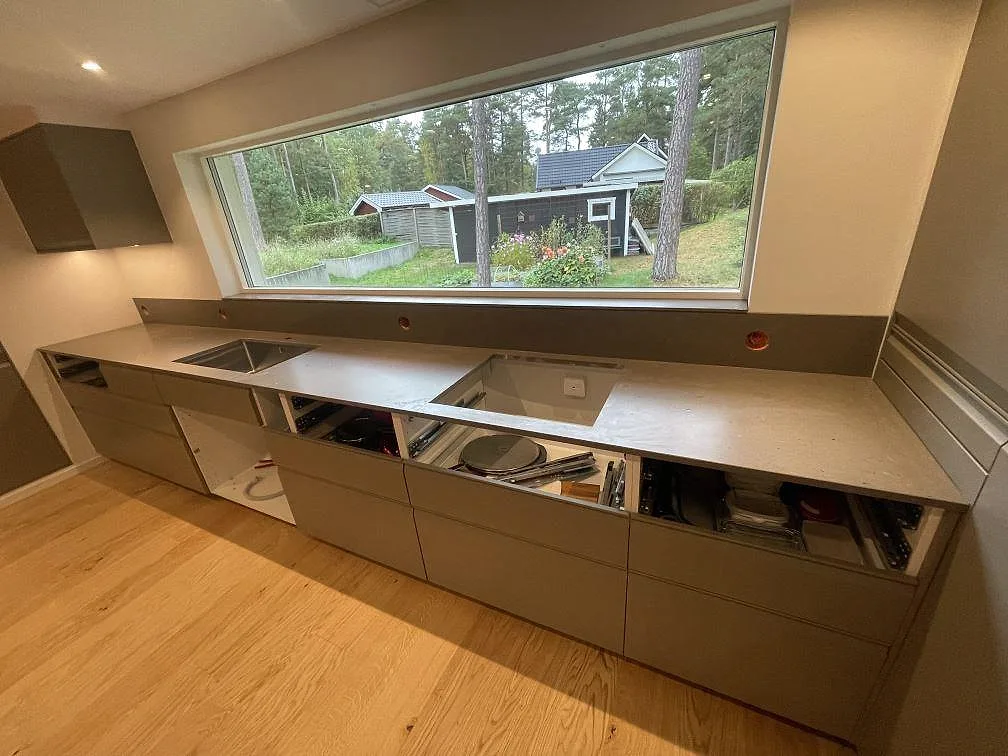 Lång köksbänkskiva i Silestone Brass Relish, matt Mocka komposit, med rostfri diskho och hällurtag under fönster i Åhus.