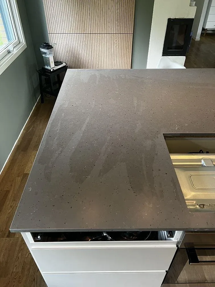 Ytdetalj på Silestone Brass Relish komposit i Mocka-finish med späcklad taupegrå stenbild i kök i Ängelholm.