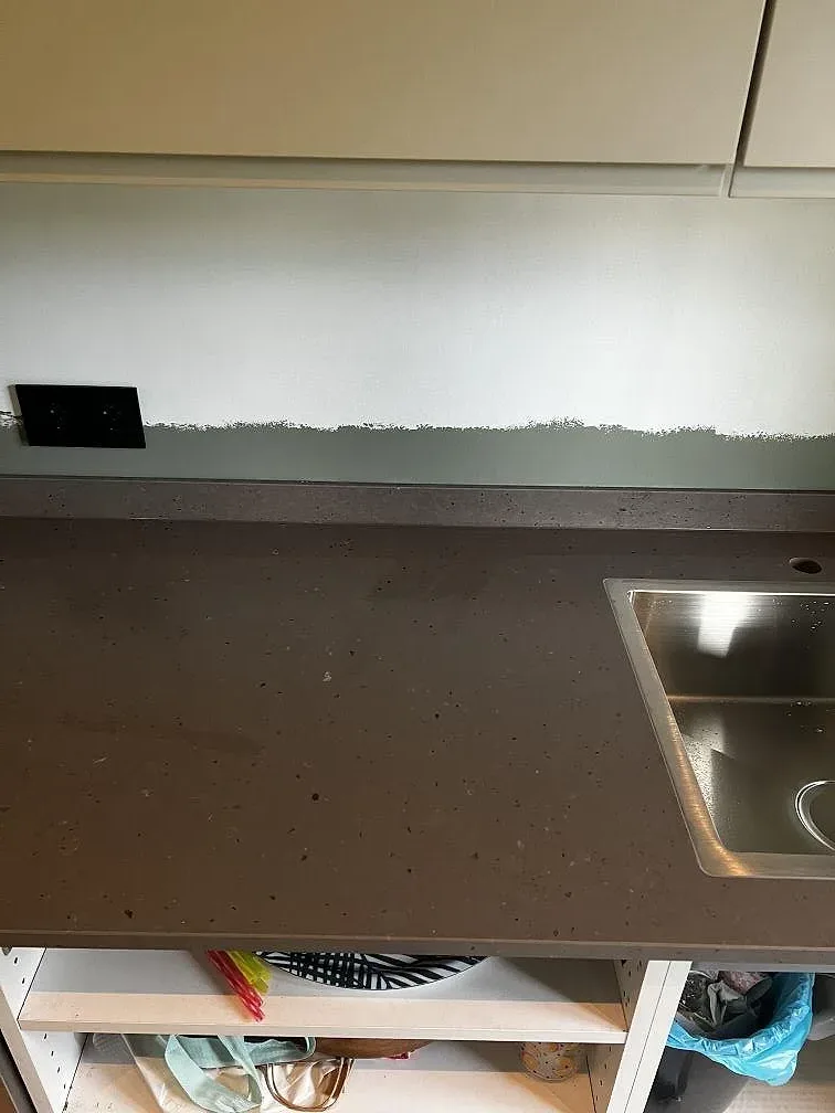 Detalj av kant och väggmöte på matt Silestone Brass Relish köksbänkskiva under montering i Ängelholm.