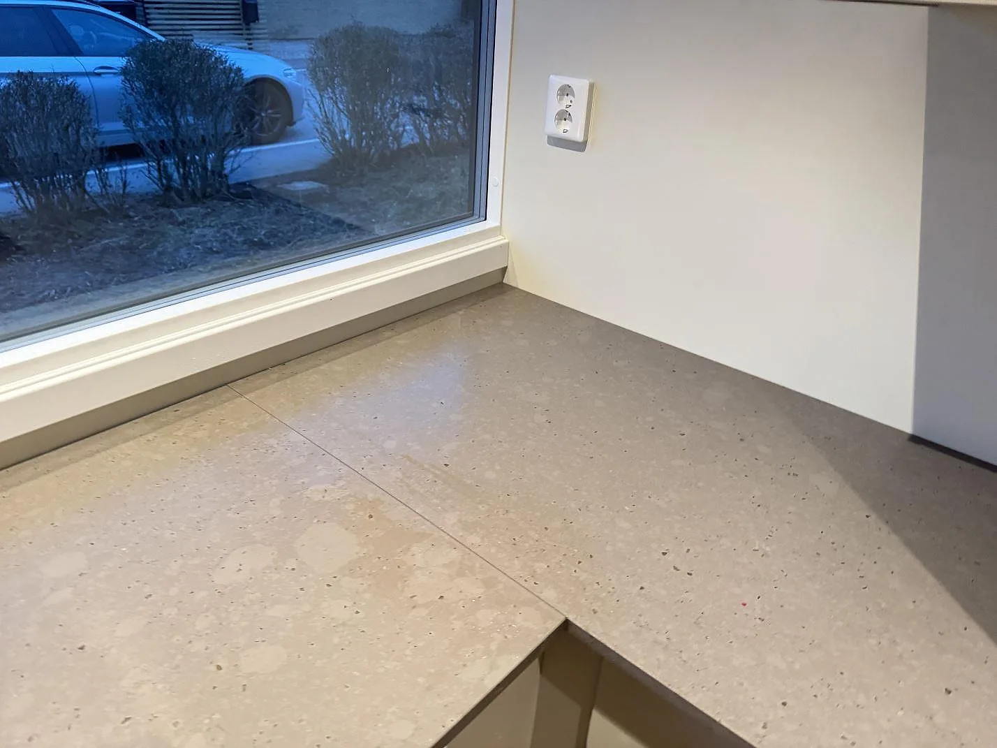 Hörndel av köksbänkskiva i Silestone Brass relish, matt Mocka-yta, under fönster i ett kök i Bjärred.