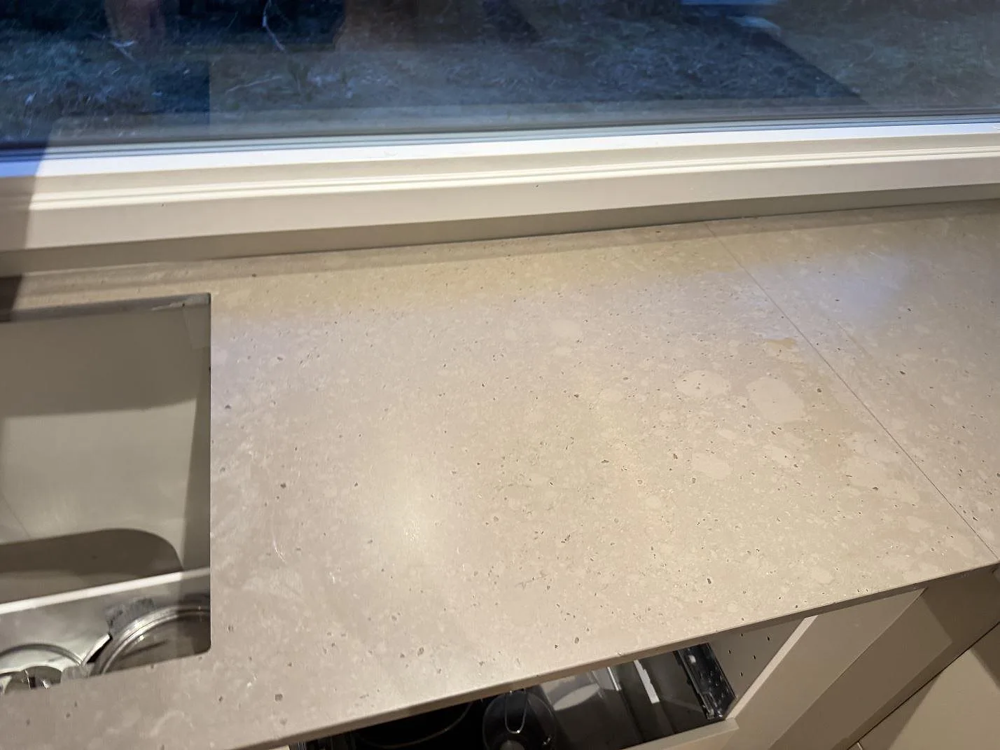 Ytdetalj av Silestone Brass relish som köksbänkskiva, matt Mocka-yta, intill diskhon under fönster i Bjärred.
