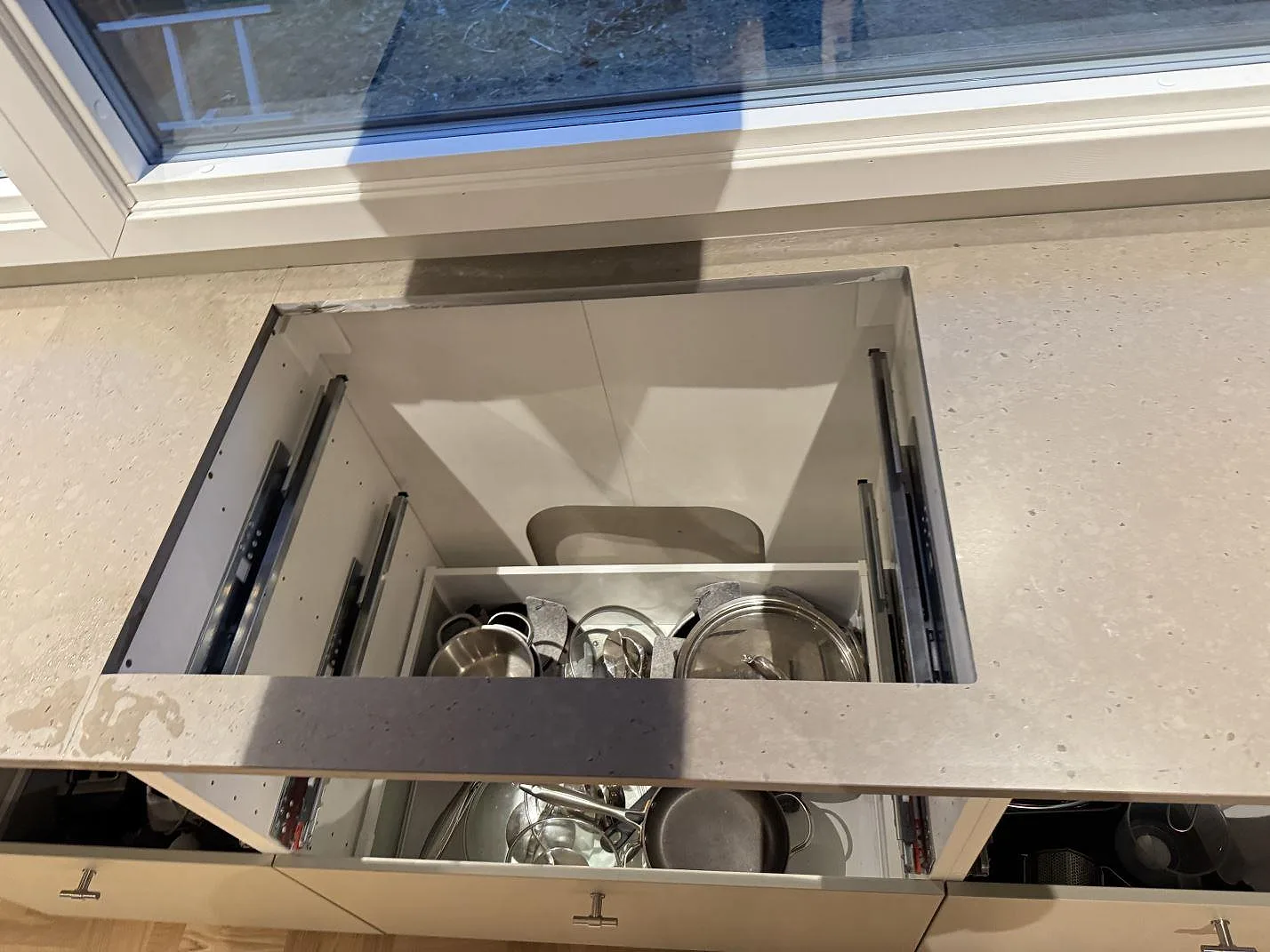Detalj av köksbänkskiva i Silestone Brass relish, matt komposit, med öppet köksskåp under montering i Bjärred.