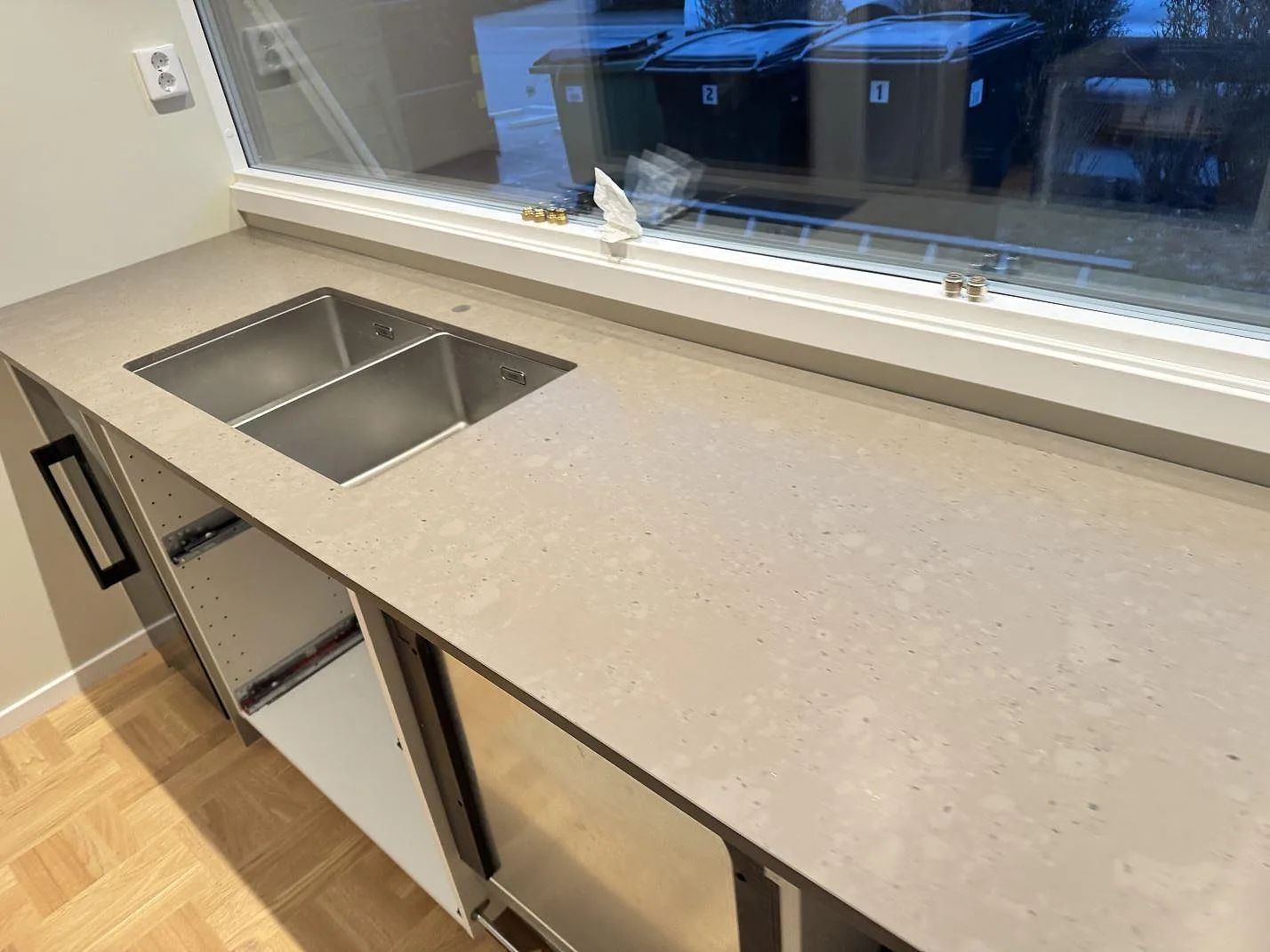 Närbild av köksbänkskiva i Silestone Brass relish, matt komposit, med rostfri dubbelho under fönster i Bjärred.