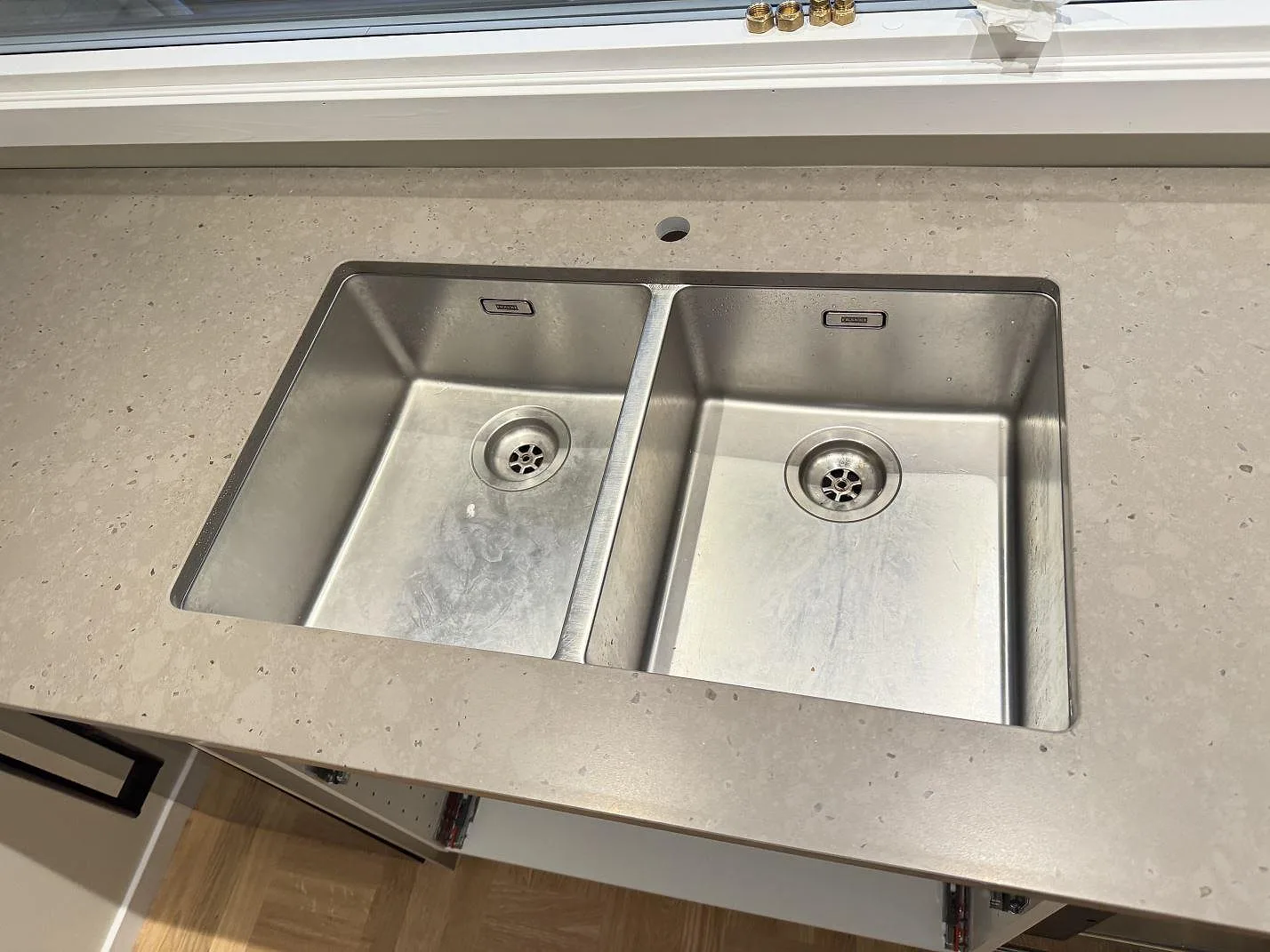 Detalj av rostfri dubbelho i köksbänkskiva av Silestone Brass relish, matt Mocka-yta, i Bjärred.