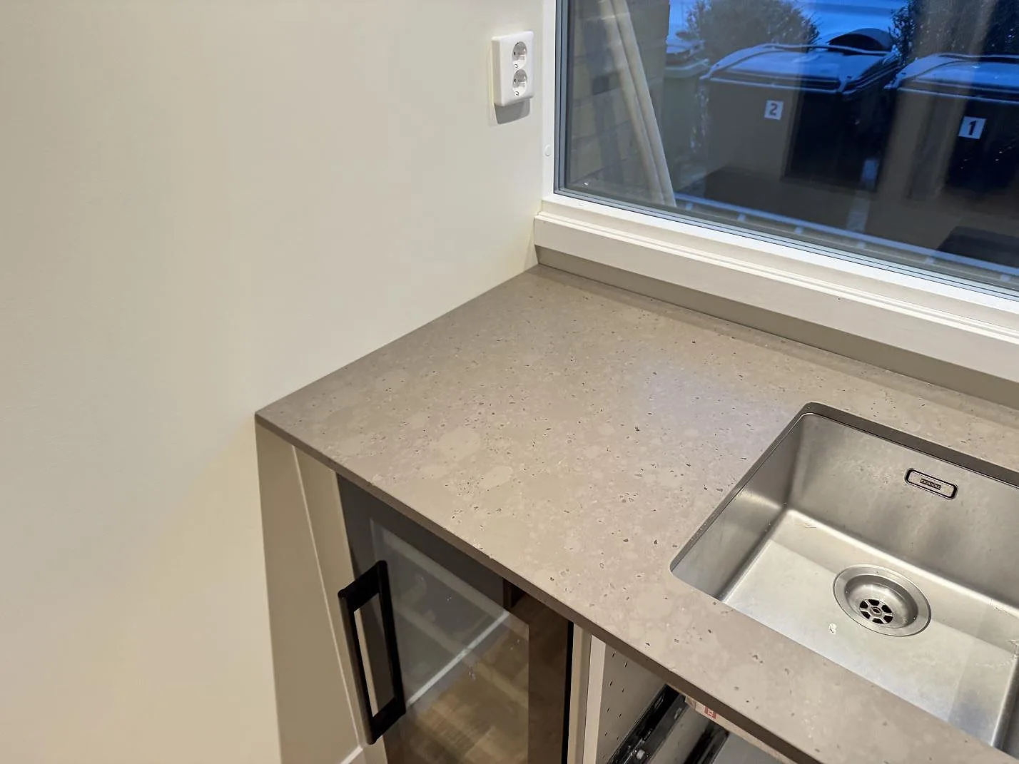 Höger hörn av köksbänkskiva i Silestone Brass relish, matt komposit, med diskho och ljusa skåp i Bjärred.