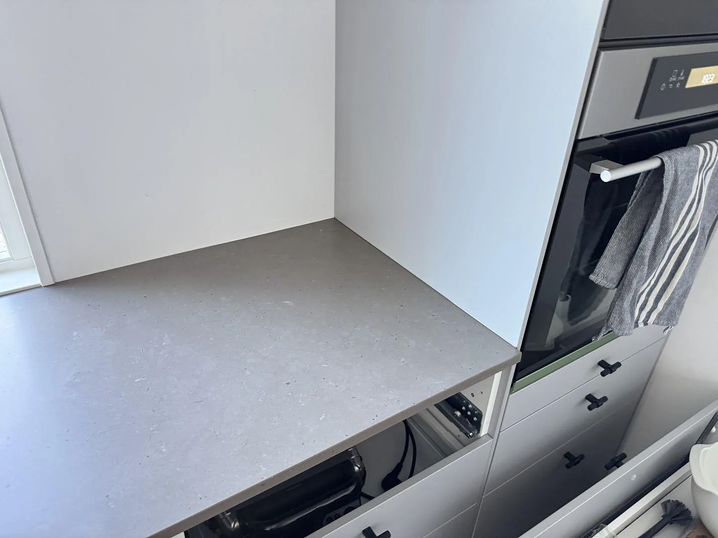 Sidodel av köksbänk i Silestone Brass relish, Mocka, intill inbyggnadsugn och vita köksstommar i Bunkeflostrand.