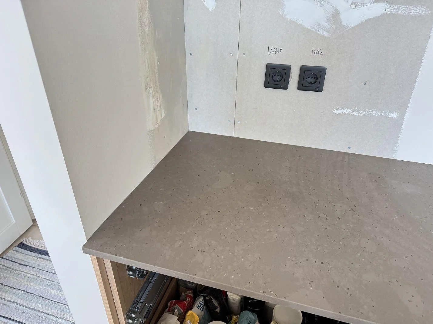 Hörn av köksbänkskiva i matt Silestone Brass relish med synliga eluttag och öppna stommar under montering i Glommen.