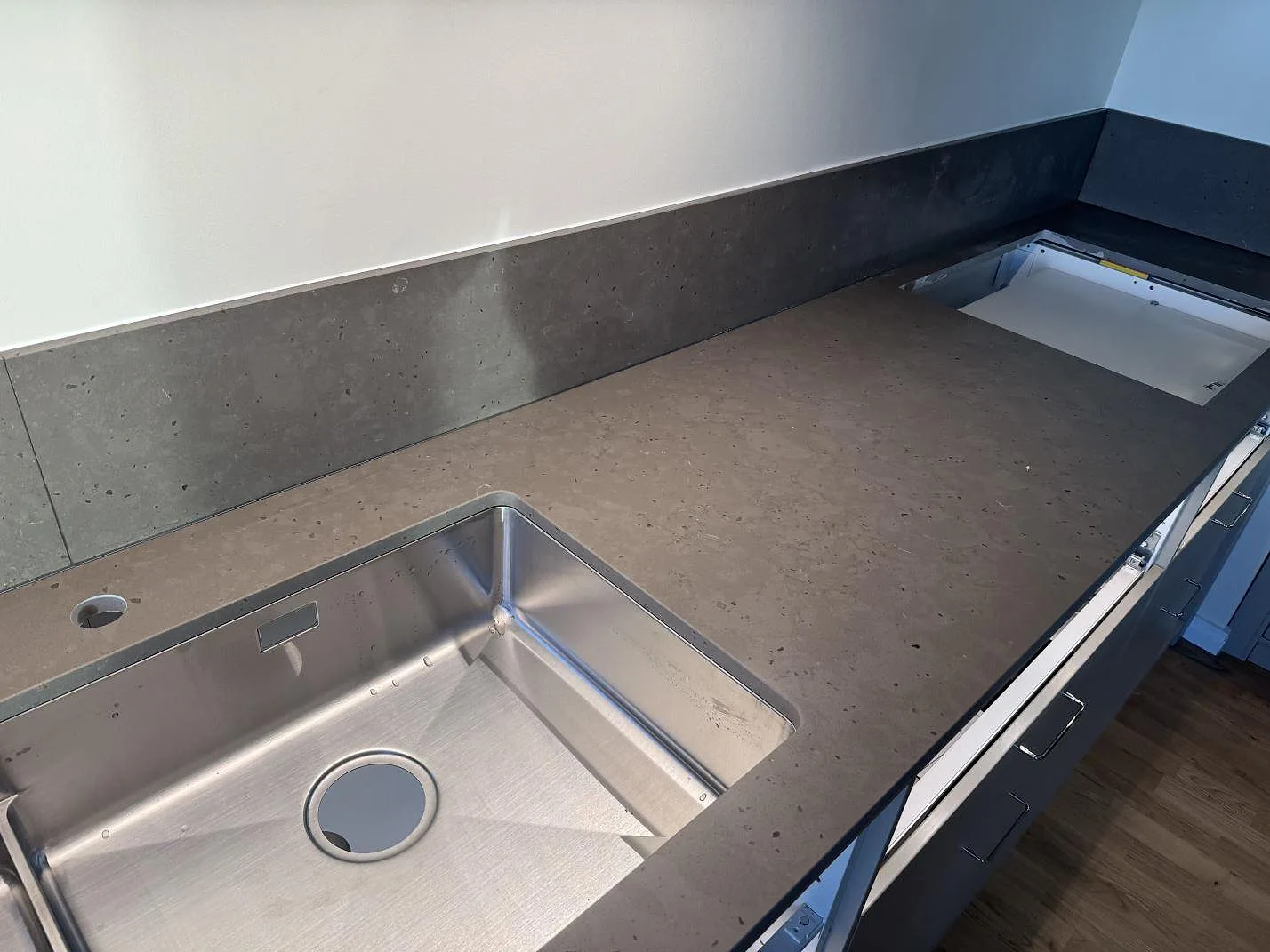 Lång köksbänk i Silestone Brass relish, matt kvartskomposit, med rostfri diskho, kranhål och stänkskydd under montering i Göteborg.
