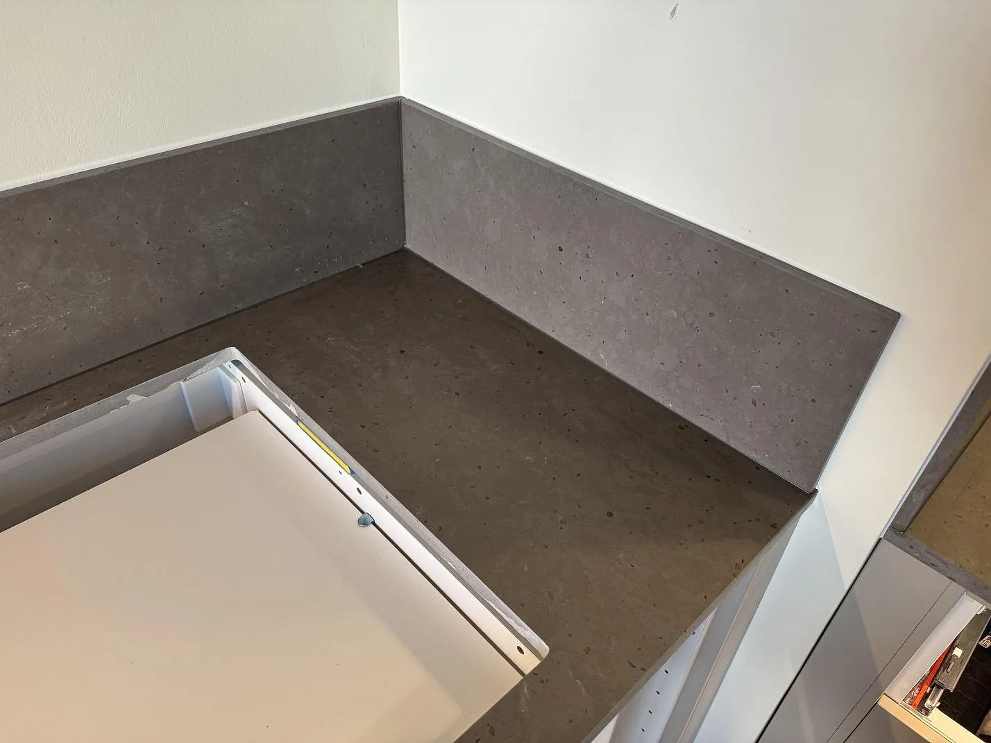 Hörnvy av Silestone Brass relish som köksbänkskiva med 12 mm stänkskydd och öppna stommar under montering i Göteborg.