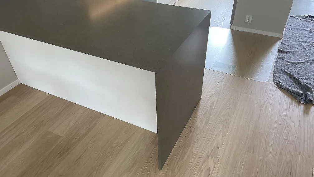 Närbild av köksö med nedvikt gavel i matt Silestone Brass relish kvartskomposit och gråbrun yta i Hjärup.