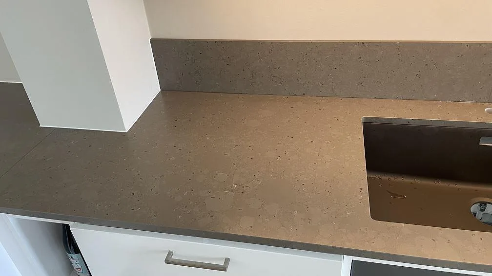 Köksbänkskiva i matt Silestone Brass relish med lågt stänkskydd och mörk ho synlig i Hjärup.