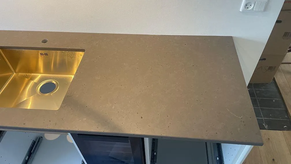 Bänkskiva i matt Silestone Brass relish med diskho, kranhål och gråbrun stenstruktur i Hørsholm.