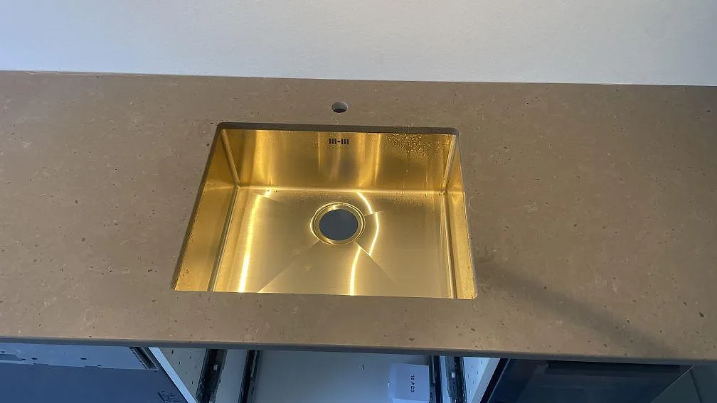 Närbild på matt Silestone Brass relish kvartskomposit med mässingsfärgad diskho i kök i Hørsholm.