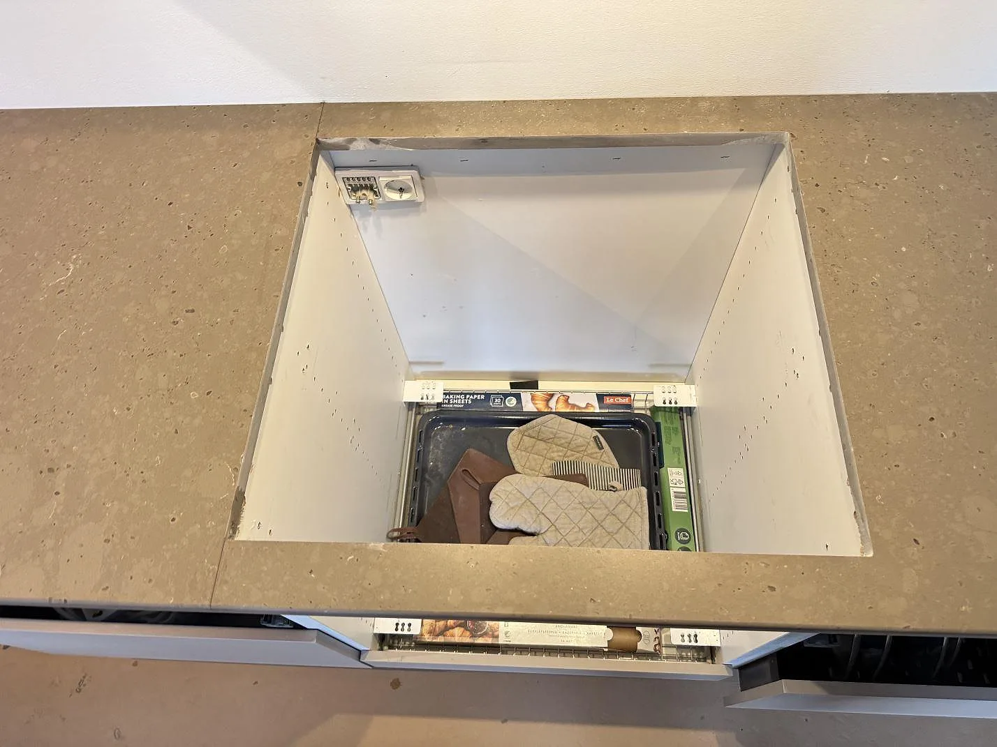 Stort hällurtag i köksbänkskiva av Silestone Brass relish, 20 mm Mocka, monterad på öppna vita stommar i Klampenborg.