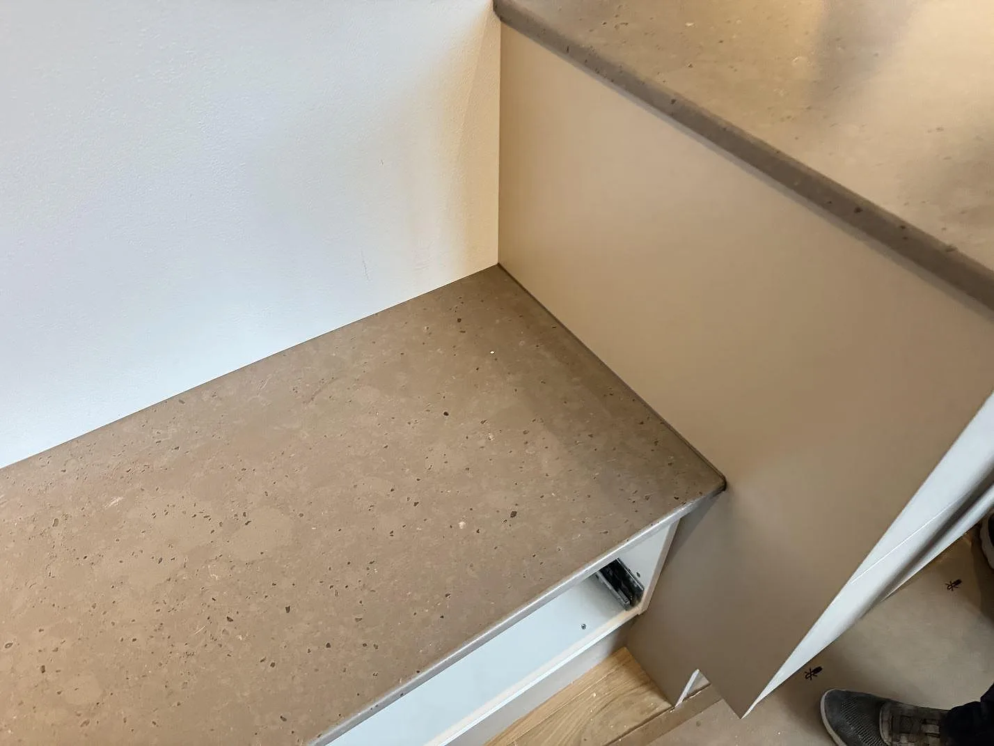 Sidobänk i matt Silestone Brass relish intill köksö och öppna stommar, fotograferad under montering i Klampenborg.
