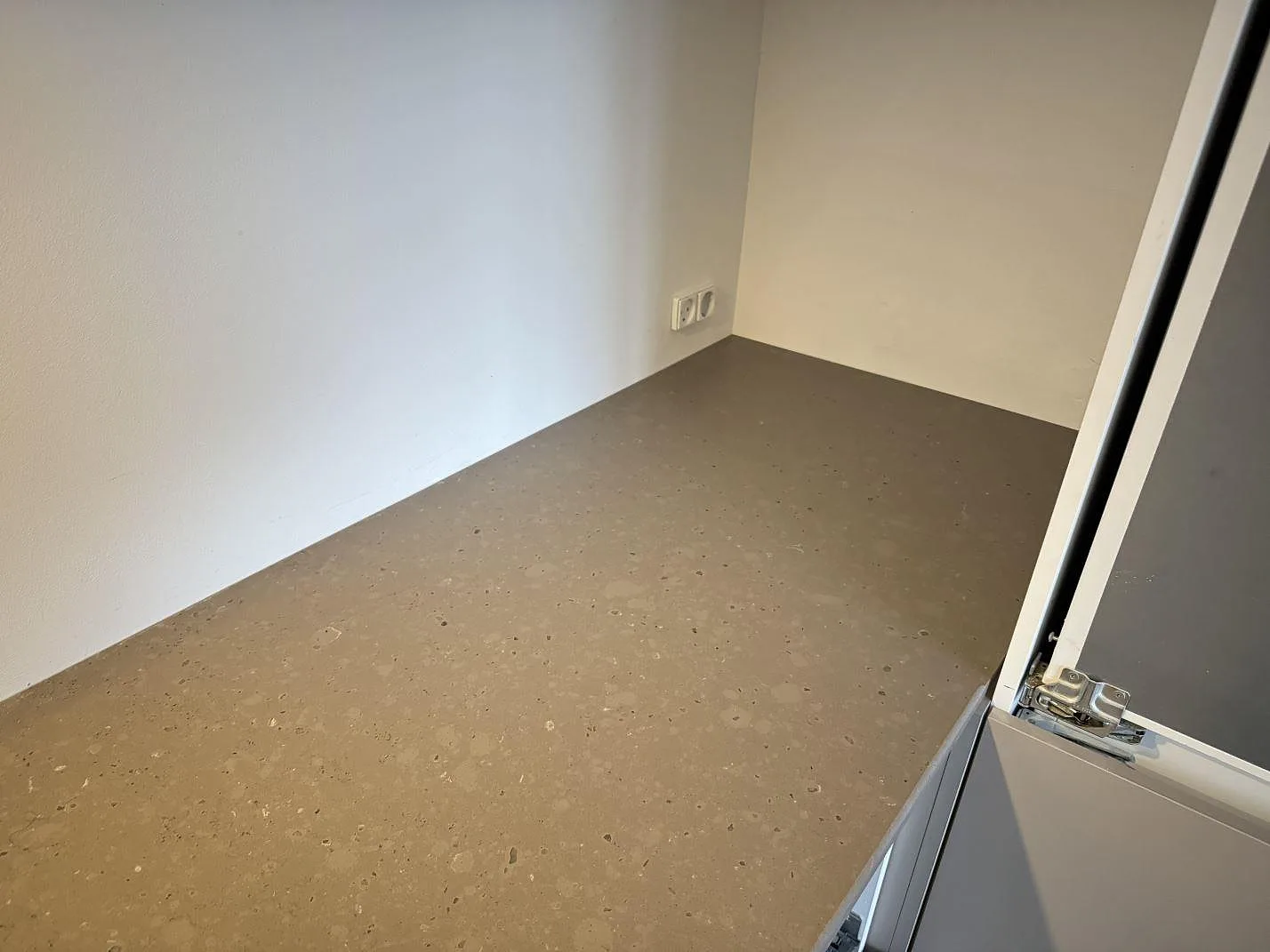 Hörndel av köksbänkskiva i Silestone Brass relish, matt gråbeige kvartskomposit, monterad mot ljusa väggar i Klampenborg.