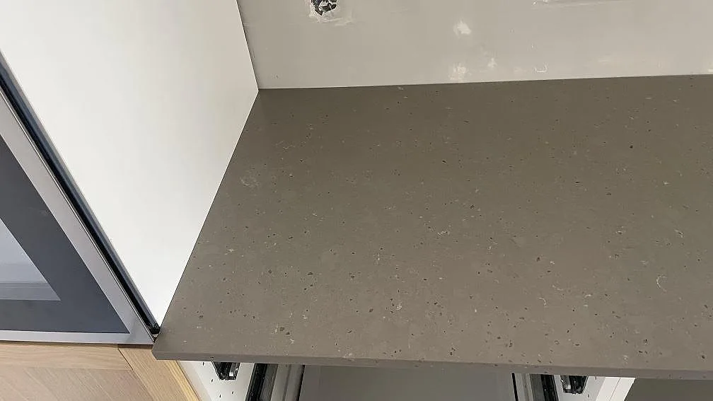 Rak bänkskiva i Silestone Brass relish längs köksväggen, matt komposit med diskret stenstruktur, i Malmö.