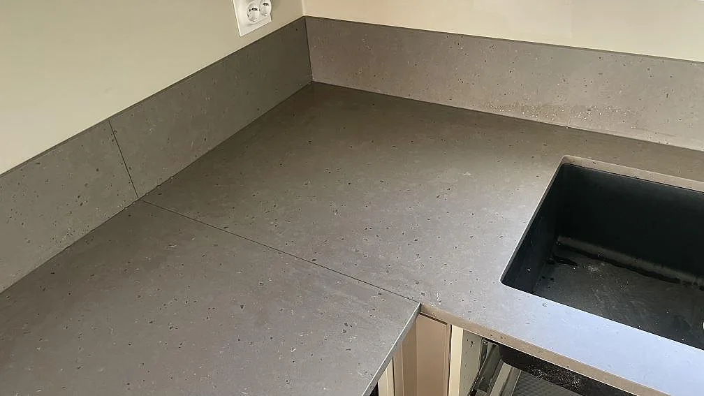Hörndel i Silestone Brass relish med matt Mocka-yta, låg stänkkant och mörk diskho i ett kök i Nättraby.
