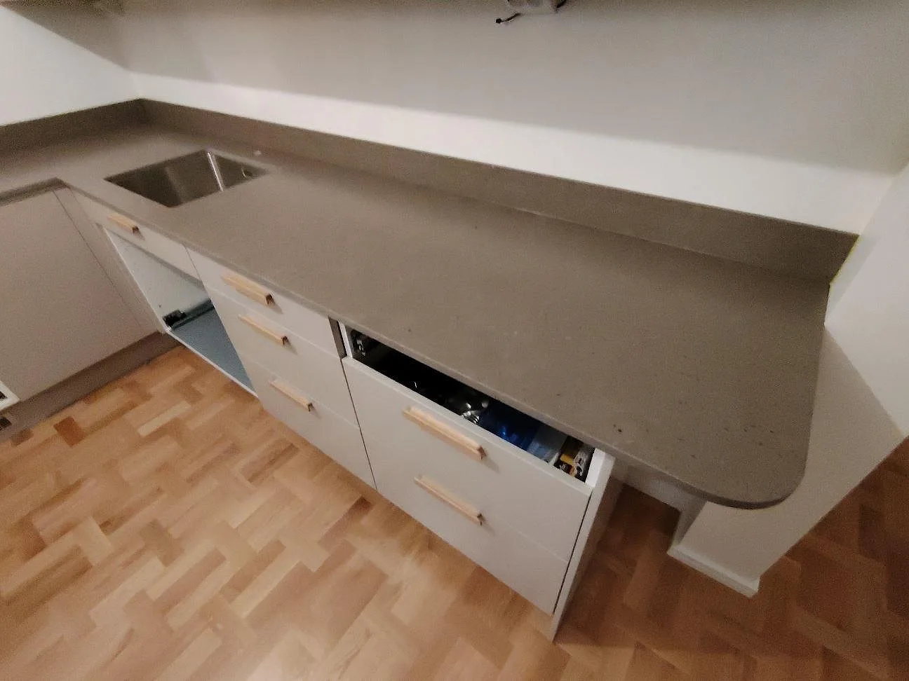 Närbild av matt Silestone Brass relish komposit längs kökets halvö med rundat avslut, diskho och låg stänkkant i Stockholm.