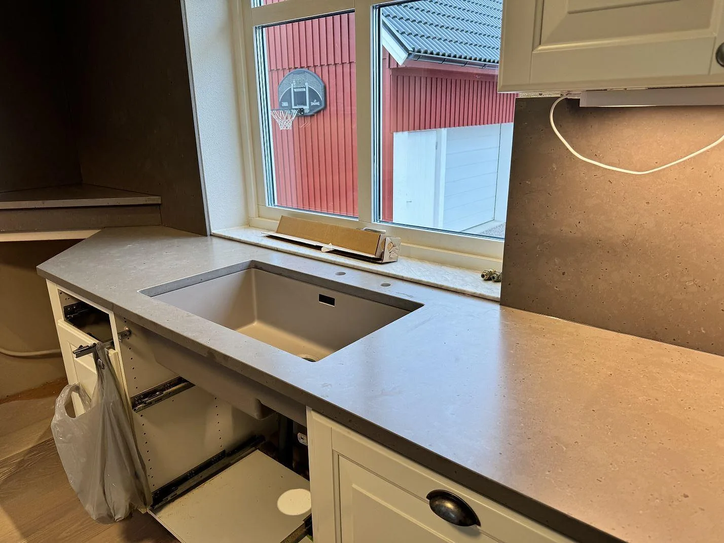 Köksbänkskiva i Silestone Brass relish, matt Mocka-yta, med ljus underlimmad diskho och stänkskydd vid fönster i Vinslöv.