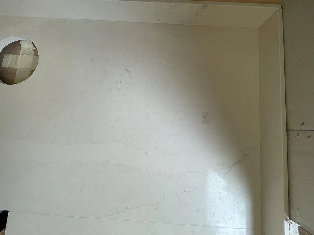 Närbild på den polerade ytan av en Silestone Calacatta Tova köksbänkskiva med mjukt grå ådring och ett förborrat hål, monterad i ett kök i Bagarmossen.