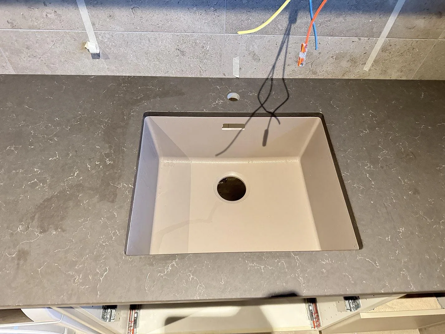 Närbild på Silestone Calypso som matt grå kvartskomposit runt en ljus ho i ett våtrum under montering i Alingsås.