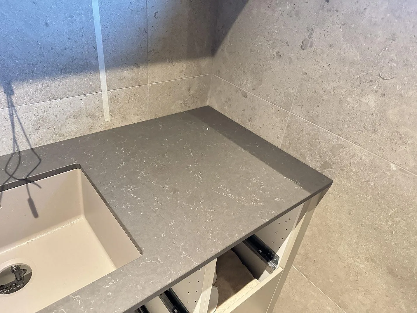 Bänkskiva i Silestone Calypso, matt kvartskomposit i 20 mm, med grå kaklade väggar och ljus ho i Alingsås.
