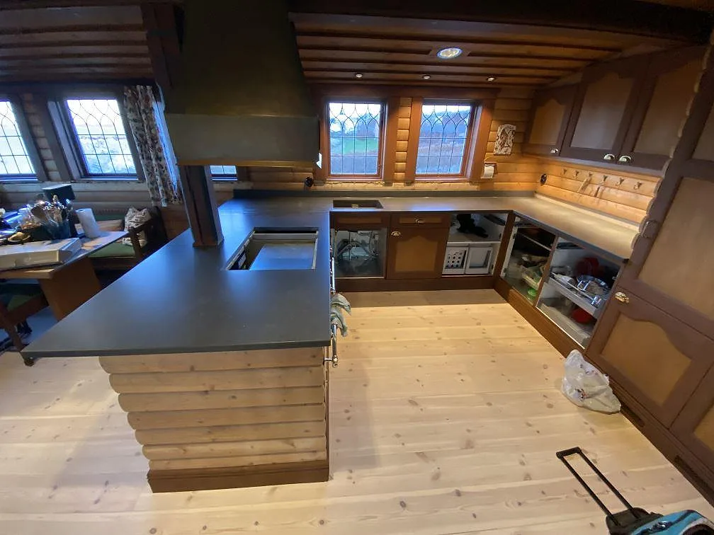Köksbänkskivor i matt Silestone Calypso, mörk kvartskomposit, med halvö, låg stänkkant och diskzon i ett kök i Båstad.