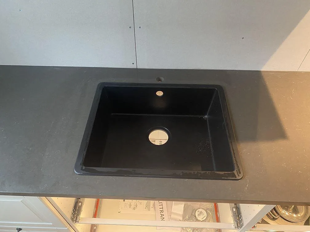 Köksbänkskiva i Silestone Calypso, polerad, med svart diskho monterad i den mörka kompositstenen i Brålanda.