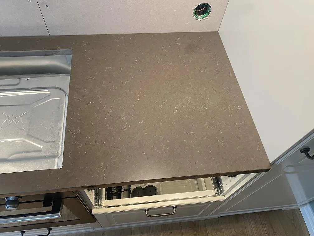 Detalj av polerad Silestone Calypso med mörk ådrad yta bredvid vitvaruöppning i köket i Brålanda.