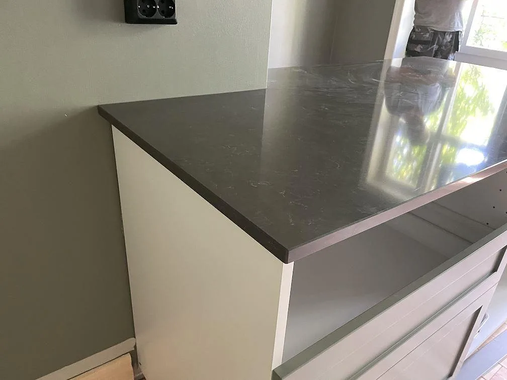 Detalj av polerad Silestone Calypso komposit med hälluttag i kökshalvön under köksmontering i Malmö.