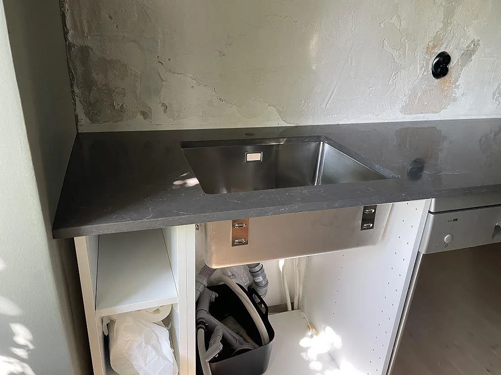 Köksbänkskiva i mörkgrå Silestone Calypso, polerad komposit, på halvö och väggbänk i ett kök under montering i Malmö.