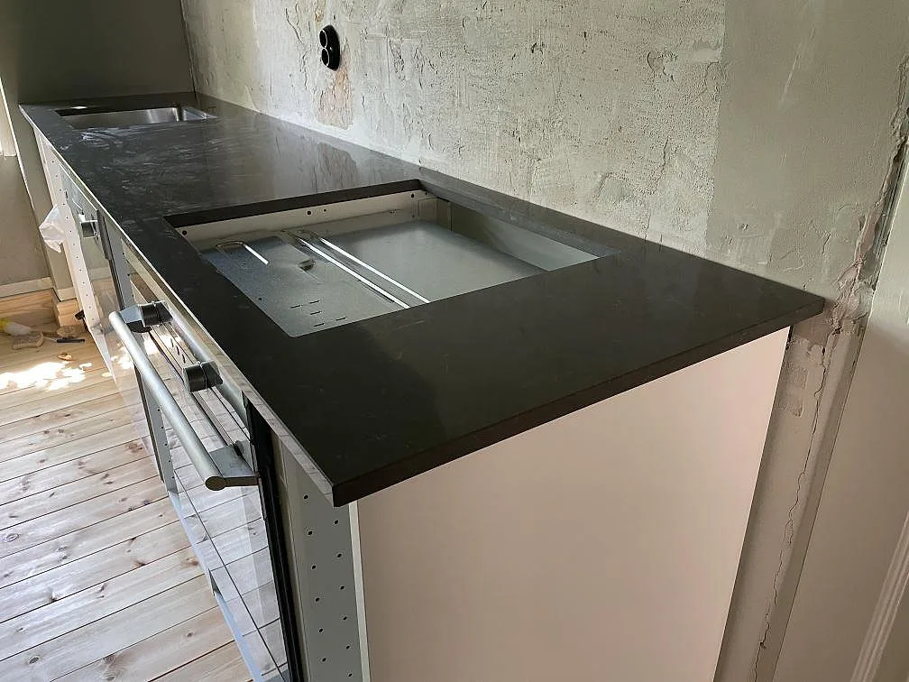 Närbild på polerad Silestone Calypso komposit som kökshalvö med mörkgrå sten och ljusa köksstommar i Malmö.