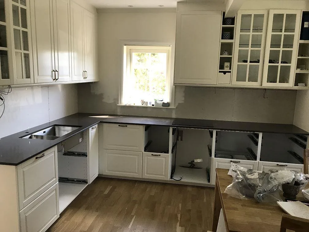 Köksbänkskiva i mörk Silestone Calypso, polerad kvartskomposit, monterad runt ett U-format kök med underlimmad diskho och induktionshäll under montering i Mölndal.