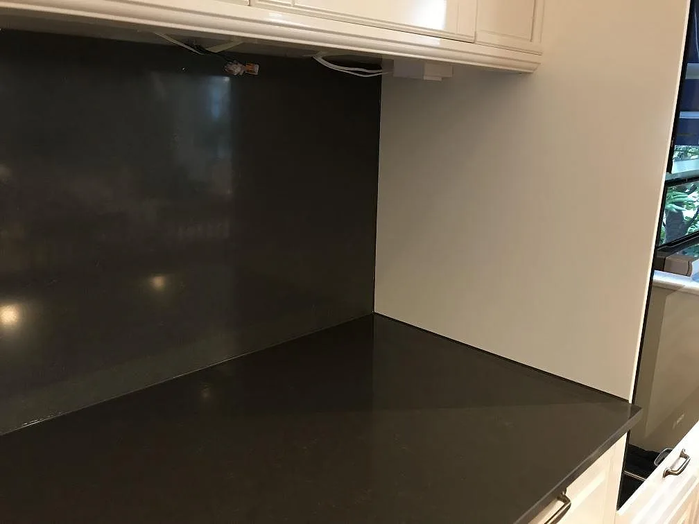 Hörnparti med köksbänkskiva och stänkskydd i mörkgrå polerad Silestone Calypso i Mölndal.