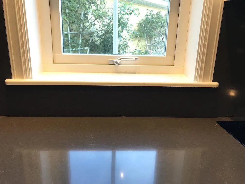 Polerad Silestone Calypso-bänkskiva under fönster med mörkt stänkskydd och hällkant i Mölndal.