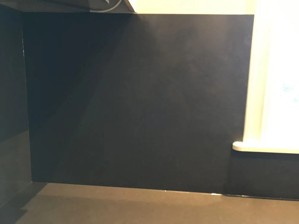 Sidovy av mörkt stänkskydd och bänkskiva i polerad Silestone Calypso vid fönster i Mölndal.