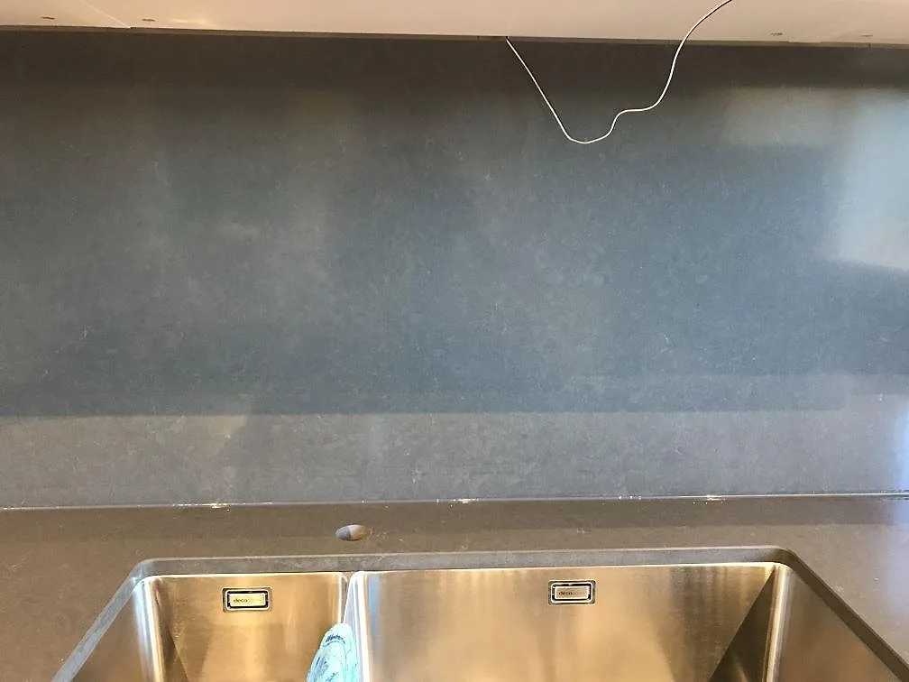 Polerad Silestone Calypso kompositbänkskiva med diskho och mörkt stänkskydd i kök i Mölndal.