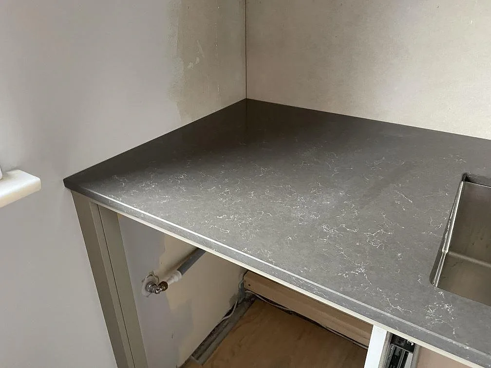 Polerad Silestone Calypso runt diskhozon med rostfri underlimmad diskho och öppen skåpstomme i Vintrie.
