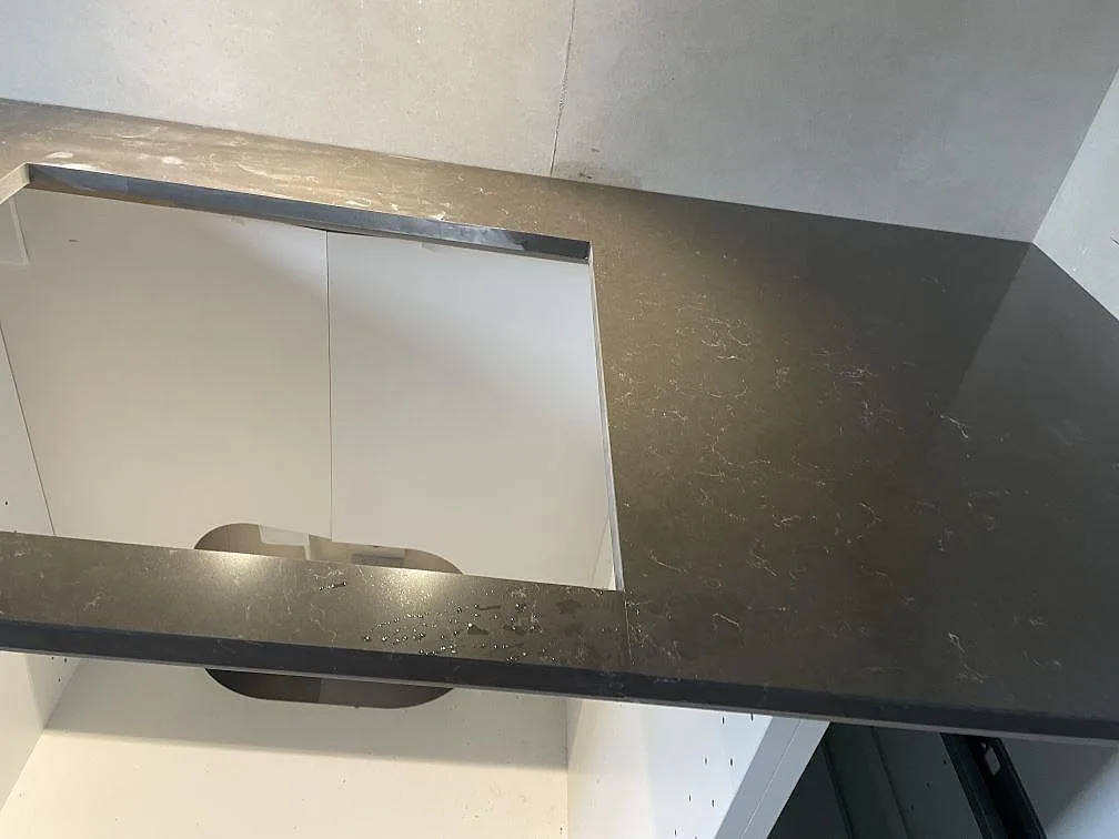 Detalj av hälluttag i polerad Silestone Calypso, grå kompositbänkskiva under montering i Vintrie.