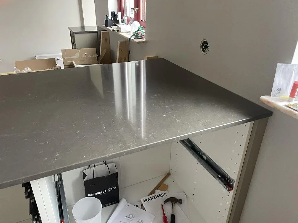 Närbild på polerad köksö i Silestone Calypso med vit skåpstomme och grå komposityta i Vintrie.