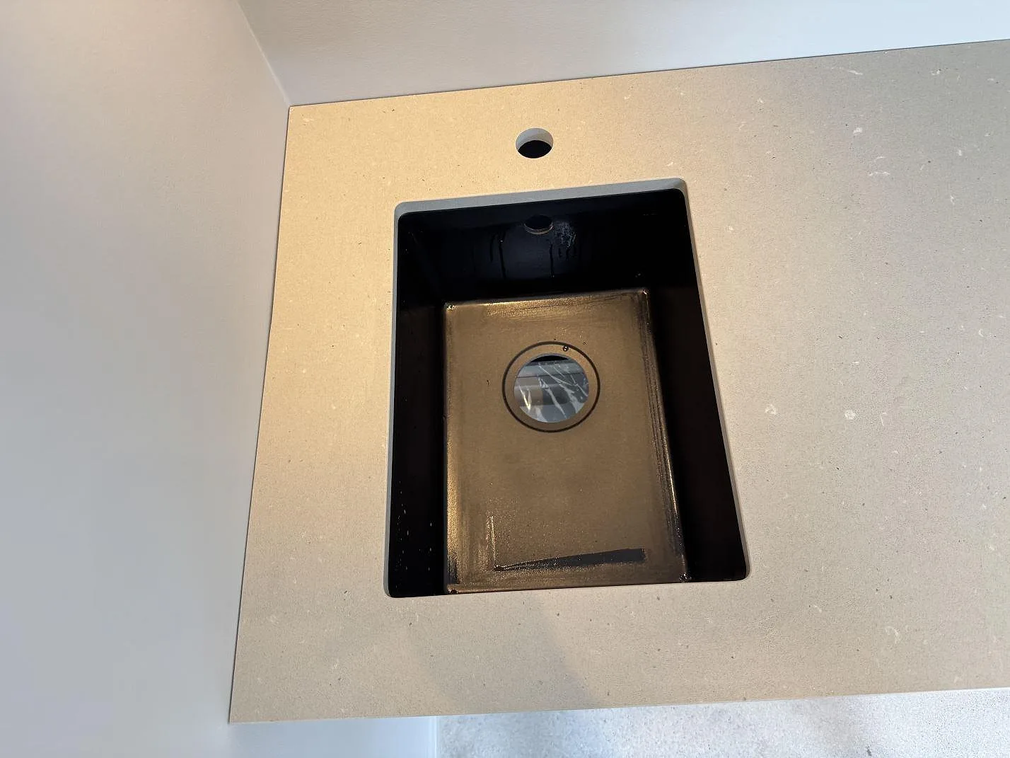 Närbild på Silestone Camden bänkskiva i matt Mocka-kvartskomposit med svart diskho och synligt blandarhål i Höllviken.