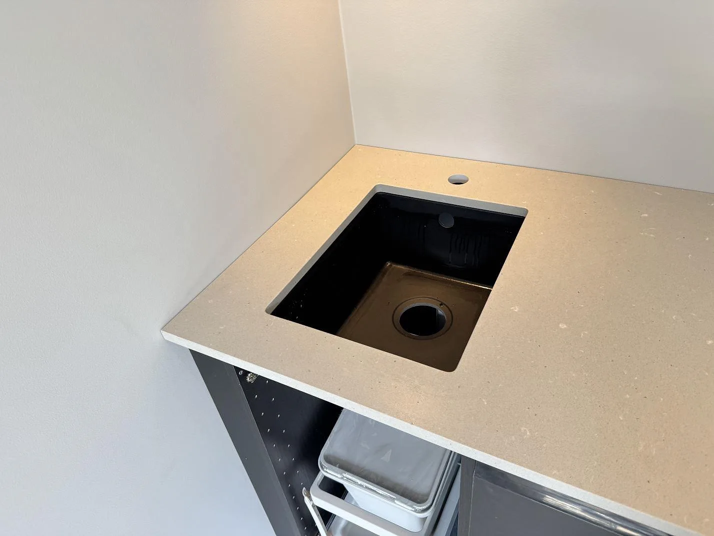 Bänkskiva i Silestone Camden, matt Mocka-kvartskomposit, med svart diskho och blandarhål i ett kök under montering i Höllviken.